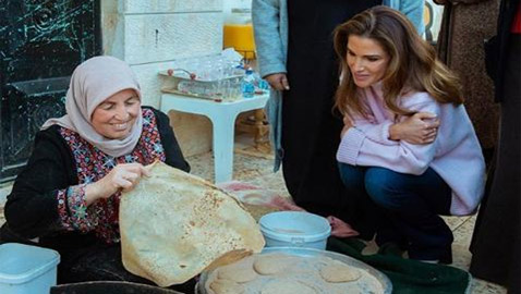 صور الملكة رانيا جالسة على الارض بجوار فرن الخبيز لتشجيع المتطوعات